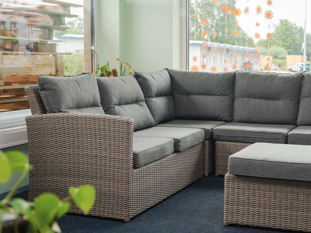 Komfortable Outdoor-Lounge mit Polyrattan-Sofa und grauen Polstern im ROXX Showroom