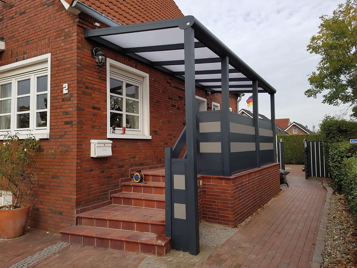 Überdachter Eingangsbereich mit Treppenaufgang und Zaunelementen und Handlauf