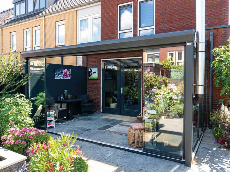 Angebaute Aluminium-Terrassenüberdachung mit Glasdach und seitlichen Glasschiebewänden