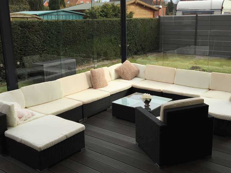 Gemütlicher Lounge-Bereich in einer geschlossenen Terrassenüberdachung mit Glasschiebewänden